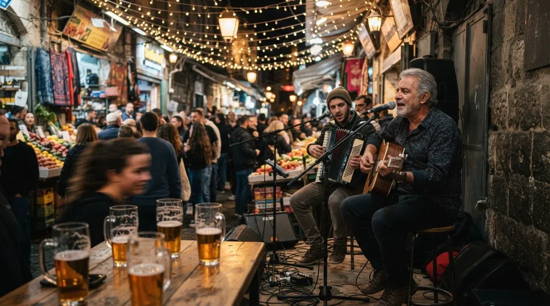 Freddy Lemon en el shuk de noche, músicos tocando bajo luces de cuerda mientras los vasos de cerveza atrapan el resplandor